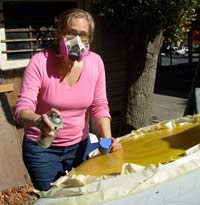 Jackson Street Youth Shelter Director, Ann Craig, dons a mask to help paint the art van's hood.